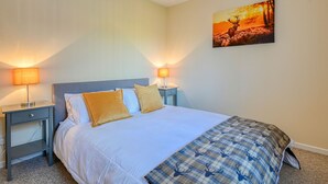 A bedroom with a bed, two bedside tables, and a wall-mounted painting.