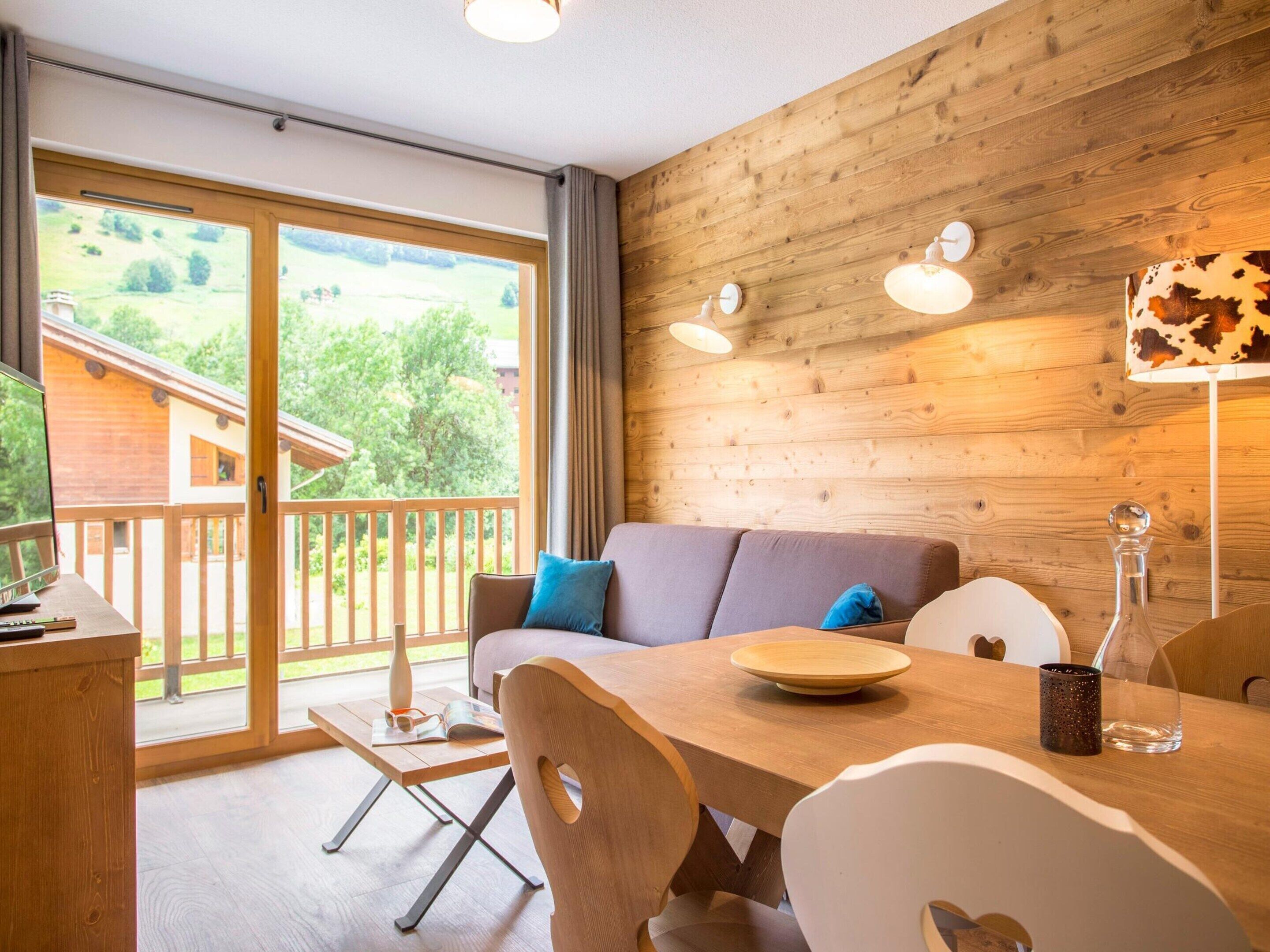 A cozy room with a wooden interior, a sofa, a dining table, and a view of the outdoors.