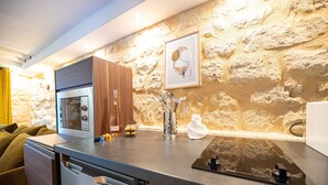 Une cuisine moderne dotée d’un four encastré, d’une machine à café et d’un mur en pierre en arrière-plan.