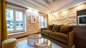 Un salon chaleureux avec un mur en pierre, un canapé, une table basse et un téléviseur.