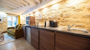 Une cuisine compacte avec un mur en pierre, des armoires en bois, un four encastré et un évier.