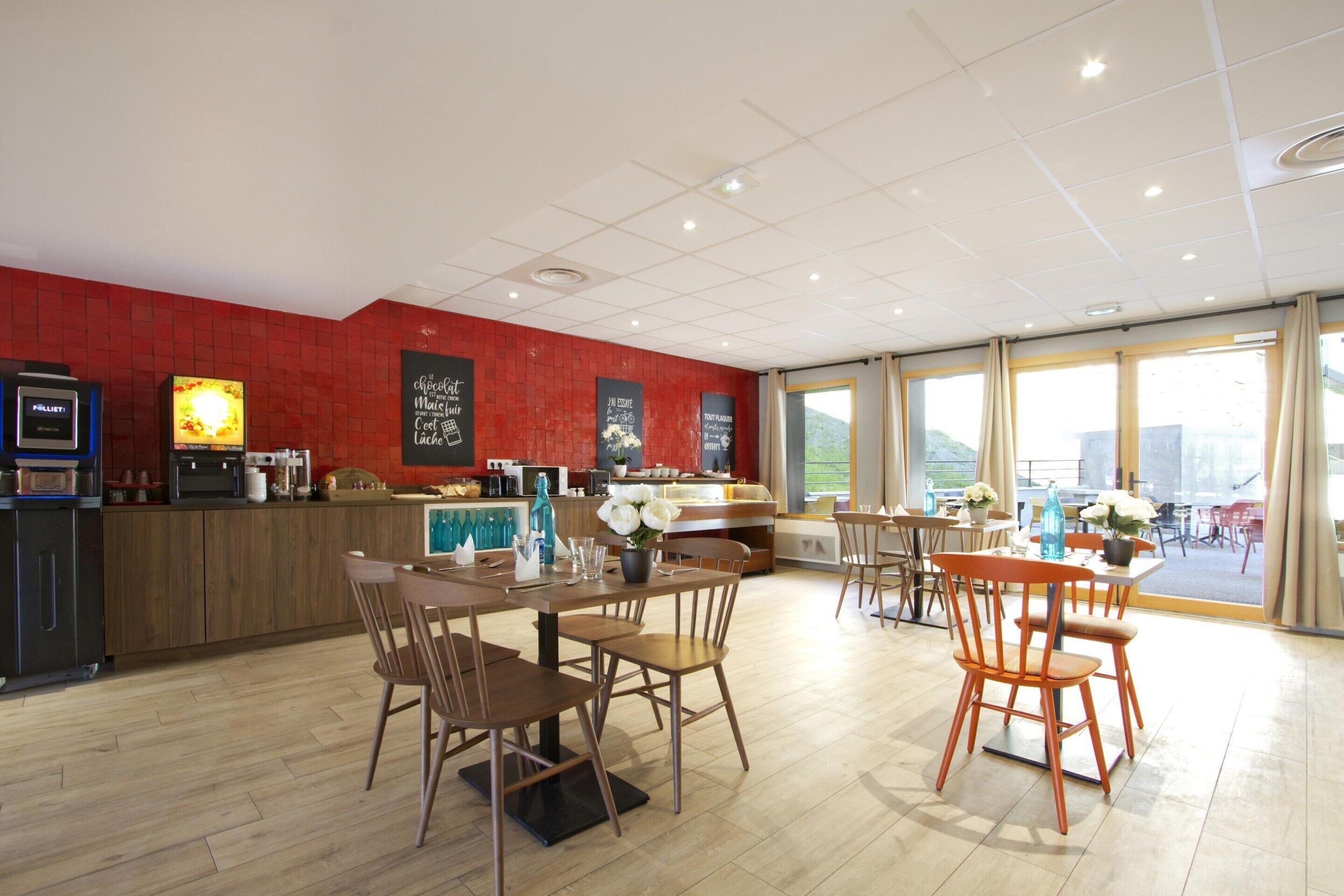 Un restaurante moderno con mobiliario de madera, una zona de bar y ventanas amplias que ofrecen vistas.