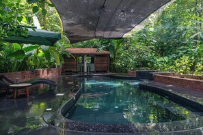A pool area with a small building, lounge chairs, and surrounding greenery. - Mojigao Eco Resort (Assagao)