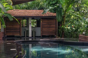 A pool area with a tiled roof structure, wooden shutters, and lush greenery. - Mojigao Eco Resort (Assagao)