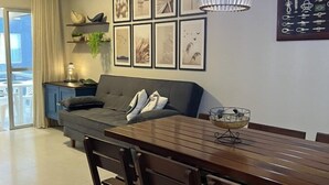 Een moderne eetruimte met een houten tafel en stoelen, een bank en een wand met ingekaderde foto's.