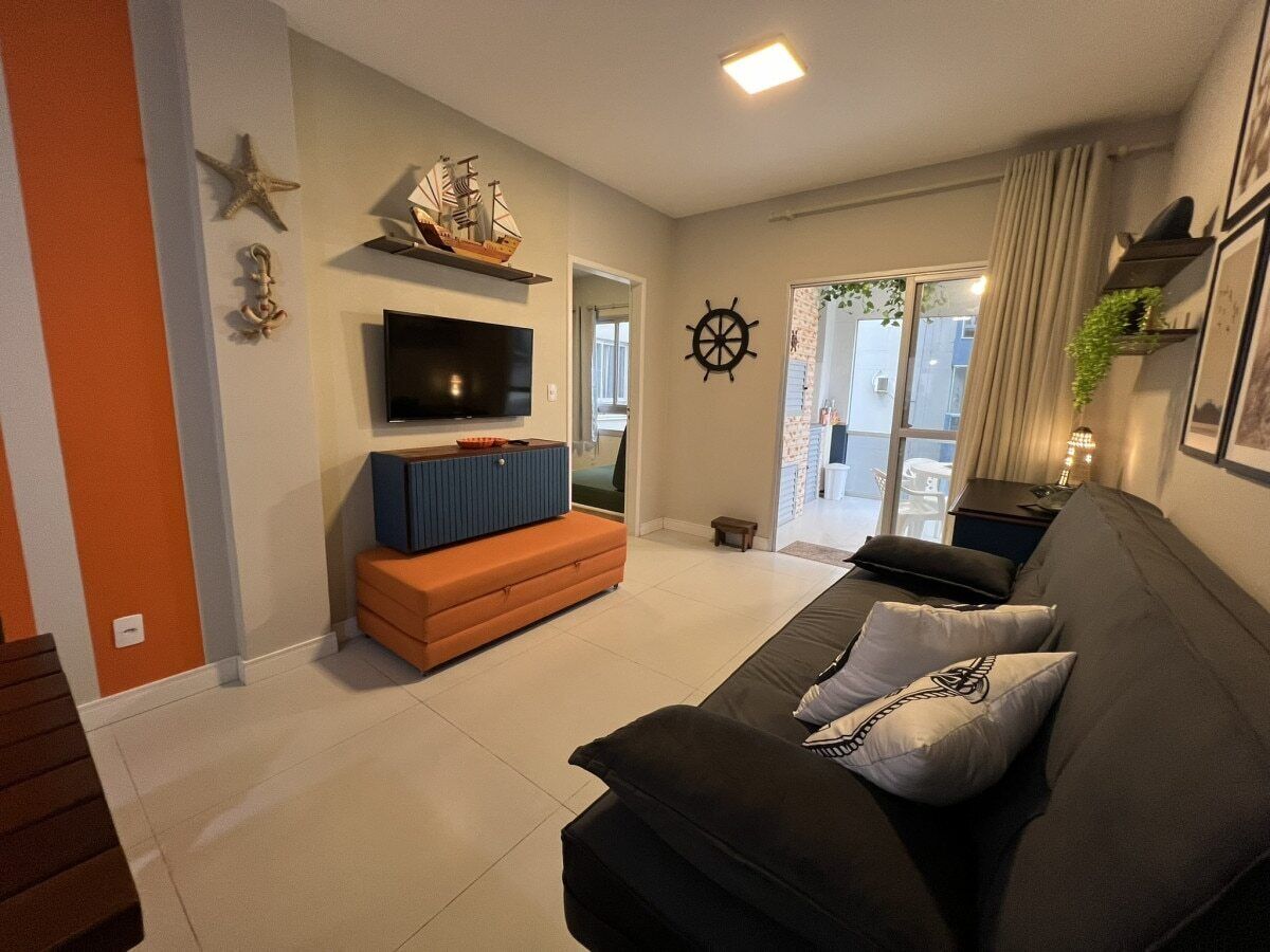 A living room with a sofa, a TV, a small table, and a ship decoration on the wall.
