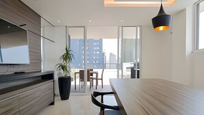 A modern kitchen with a large dining table, a potted plant, and a view of the city through large windows. - Studio prox shopping Curitiba Wifi, TV a Cabo e ar (Curitiba)