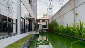 A modern building with a reflective pool and a covered seating area. - Studio prox shopping Curitiba Wifi, TV a Cabo e ar (Curitiba)