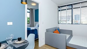 Una habitación moderna con zona de comedor, sofá y cama.