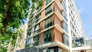 Un edificio de varios pisos con un diseño arquitectónico moderno, que presenta grandes ventanales y una combinación de fachadas de ladrillo y vidrio.