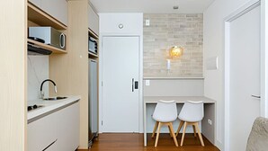 Une cuisine compacte dotée d’appareils électroménagers modernes, un coin repas avec deux chaises et une petite table.