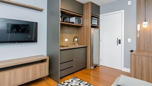 A modern kitchen with built-in appliances, a flat-screen TV, and a wooden bench.