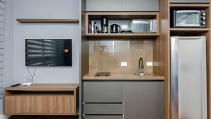 A modern kitchen with a built-in microwave, coffee maker, and a stainless steel refrigerator.