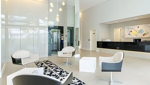Rebedor modern amb taulell de recepció, cadires blanques i una catifes amb dibuixos.