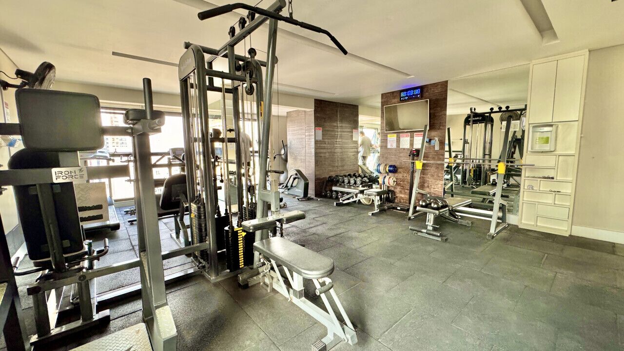 Uma academia com diversos equipamentos de exercícios, incluindo máquinas de peso e halteres.