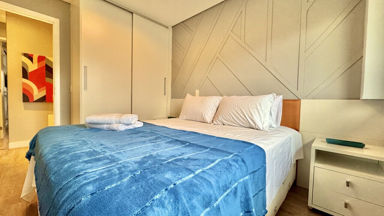 Una habitación de hotel moderna con una cama grande, una mesita de noche y un armario.