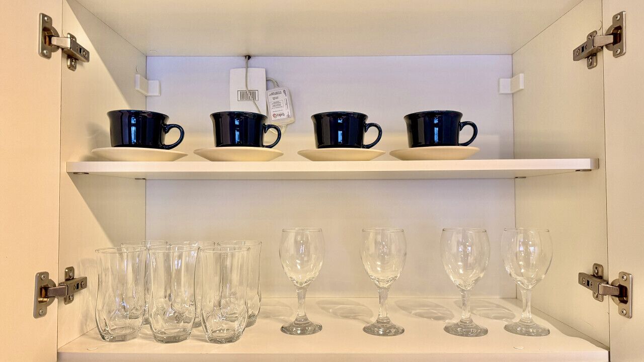 Un meuble de cuisine contenant de la verrerie noire et transparente.