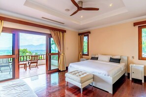 Relax on the balcony with a view of the surrounding landscape, featuring a large bed and a small table with two chairs.