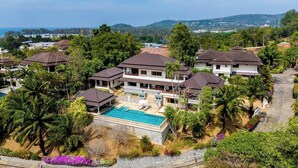 A residential area with multiple houses, a swimming pool, and lush greenery.