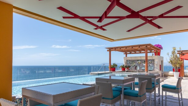 Eine Dachterrasse mit Pool, Sitzgelegenheiten im Freien und Blick aufs Meer.