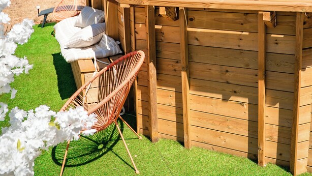 A wooden hot tub with a built-in bench and cushions, surrounded by a well-maintained lawn and a variety of trees. - Cotignac en famille - the perfect setting for your vacation (Cotignac)