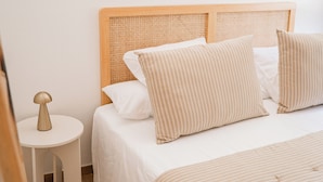 A neatly made bed with a wooden headboard, a small bedside table with a lamp, and a wooden floor. - Cotignac en famille - the perfect setting for your vacation (Cotignac)
