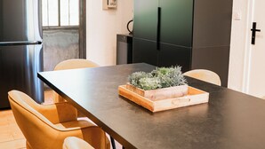 A modern kitchen with a dark countertop, yellow chairs, and a wooden sideboard with plants. - Cotignac en famille - the perfect setting for your vacation (Cotignac)
