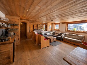 En inredning med träpanel, en soffa, ett soffbord och hyllor med köksutrustning.