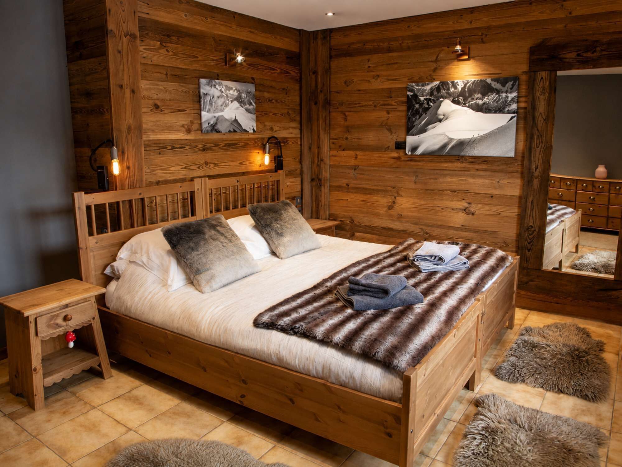 Un dormitorio de madera con cama, mesitas de noche y cómoda.