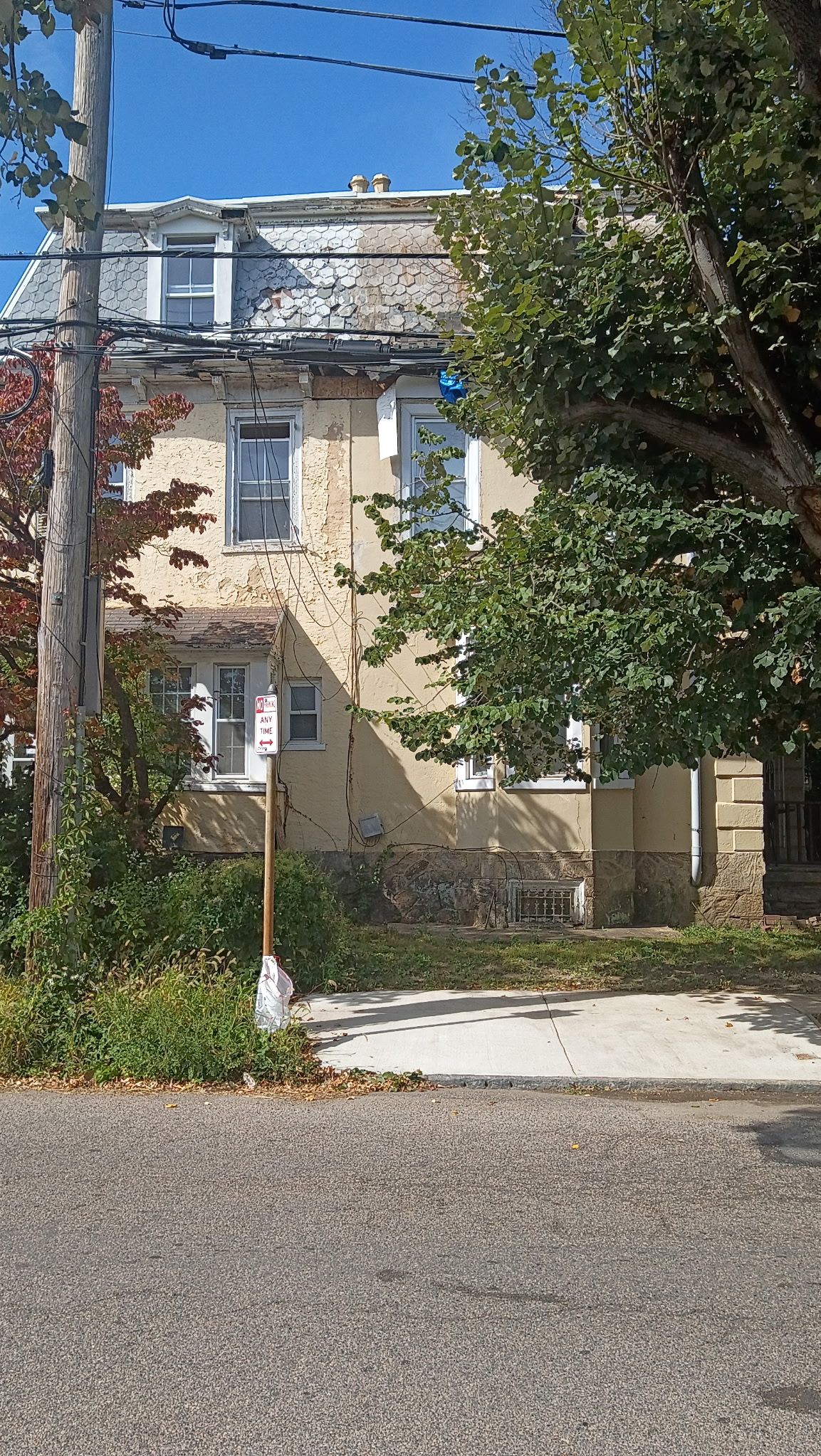 A two-story building with a stone facade, a visible window, and a street sign.
