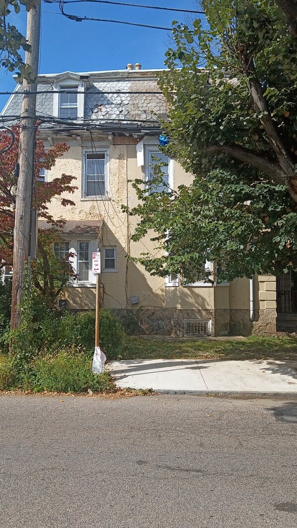 Un edificio de dos pisos con fachada de piedra, una ventana visible y una señal de calle.