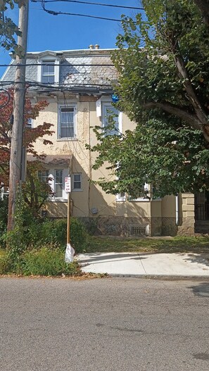 A two-story building with a stone facade, a visible window, and a street sign.