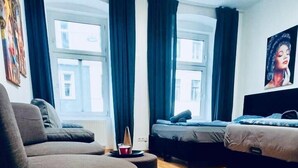 Ein modernes Wohnzimmer mit einer Couch, einem Hocker und zwei Betten.