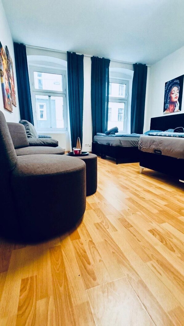 Una sala de estar moderna con sofá, reposapiés y dos camas.