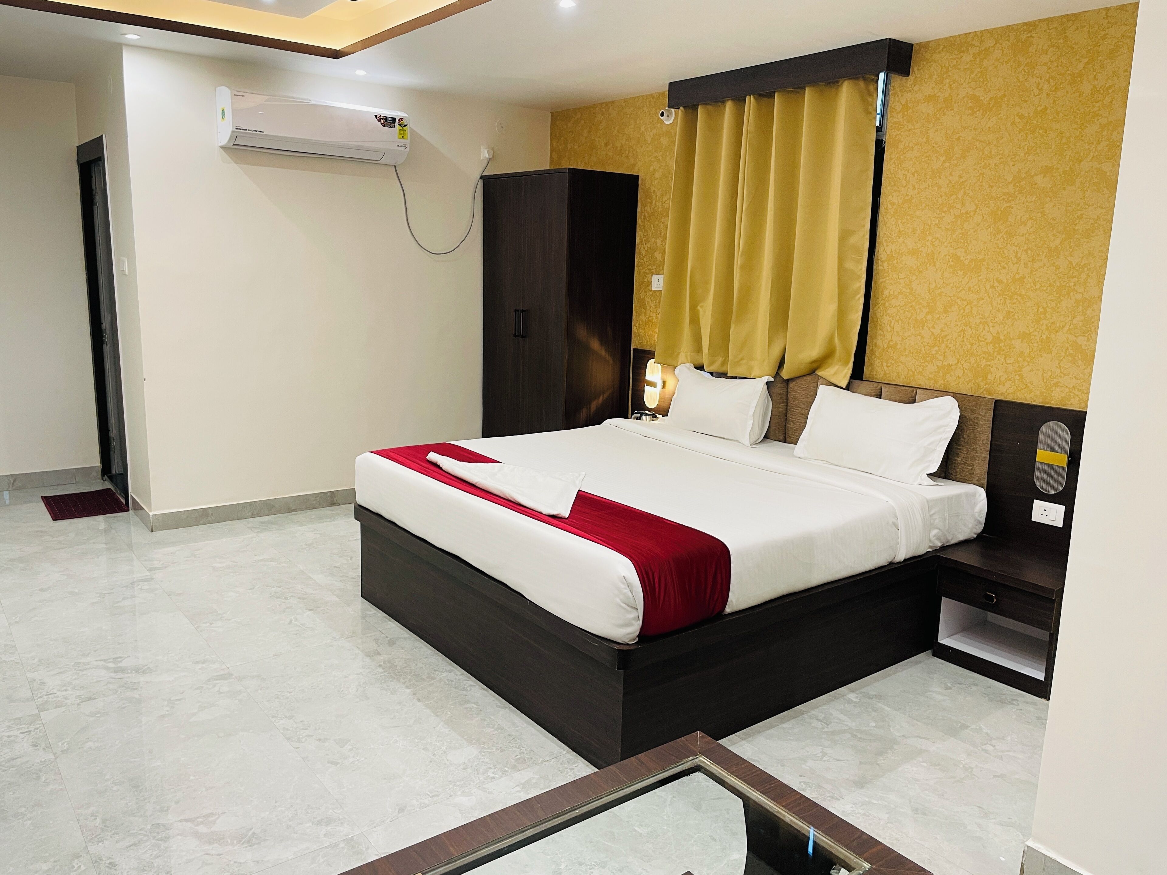 Quarto de hotel com cama, guarda-roupa, mesa de cabeceira e ar condicionado.