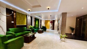 Um lobby moderno com sofás verdes, uma mesa de centro e um balcão de recepção.
