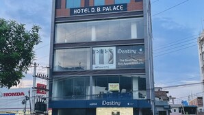 Um hotel de vários andares chamado 'Janki Palace', com um aviso de 'To-let' e uma loja 'iDestiny' no andar térreo.