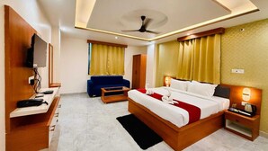 Quarto de hotel moderno com uma cama grande, uma televisão, uma escrivaninha e um sofá.