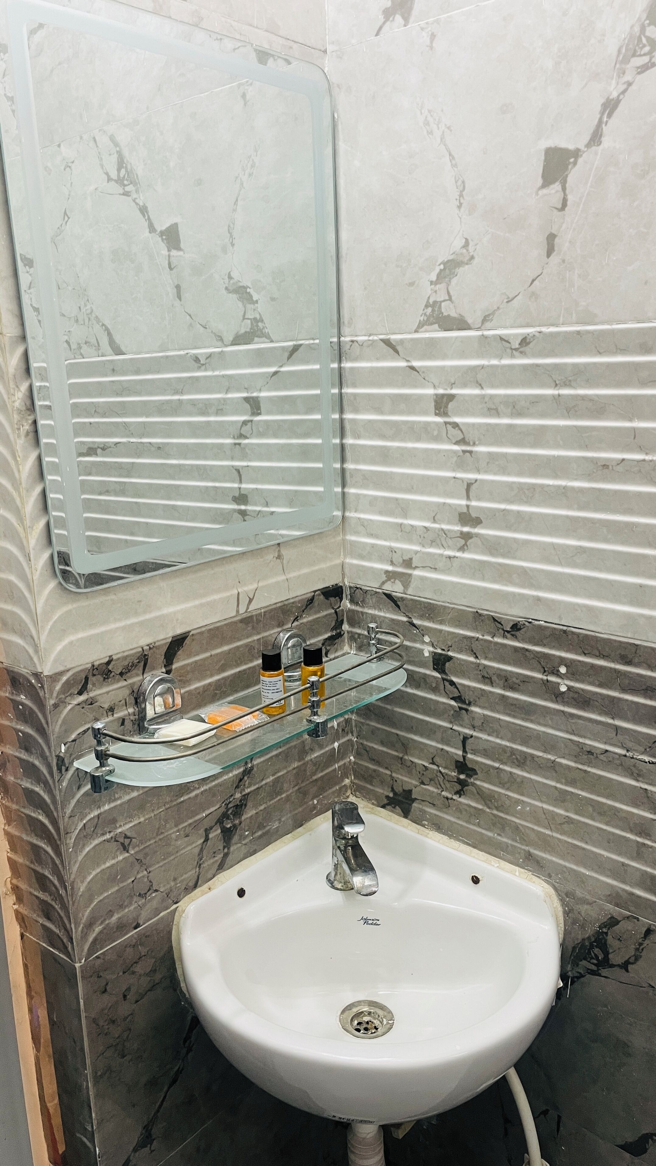A bathroom with a white sink, a glass shelf with toiletries, and a mirror above the sink.