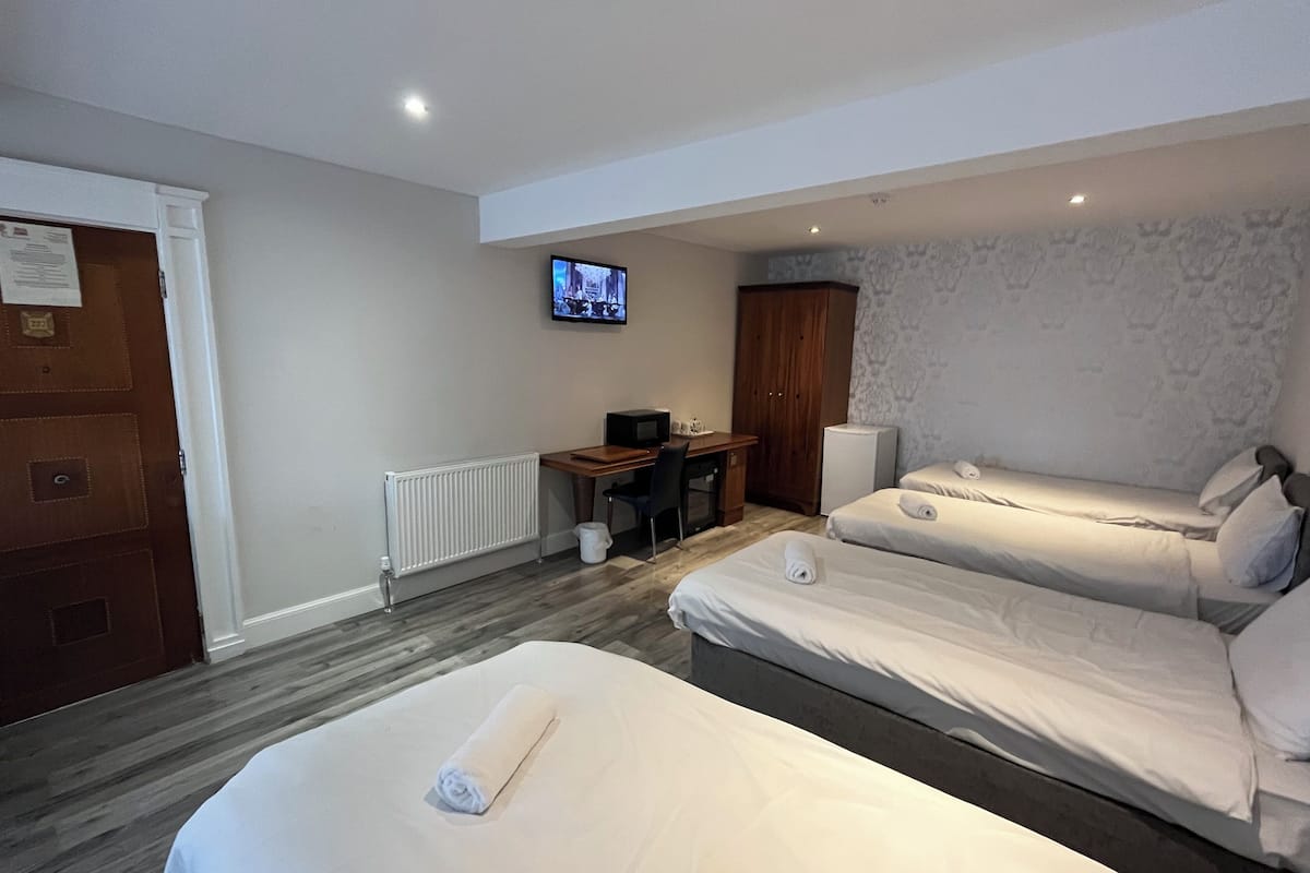 A hotel room with two beds, a desk, a television, and a wardrobe.