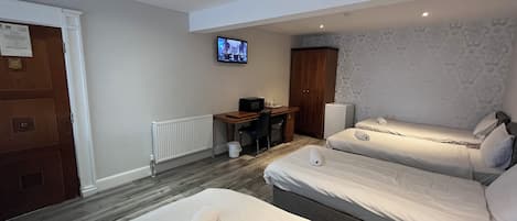 A hotel room with two beds, a desk, a television, and a wardrobe.