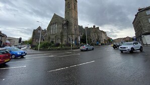 A church with a tall tower and a wet road in front.