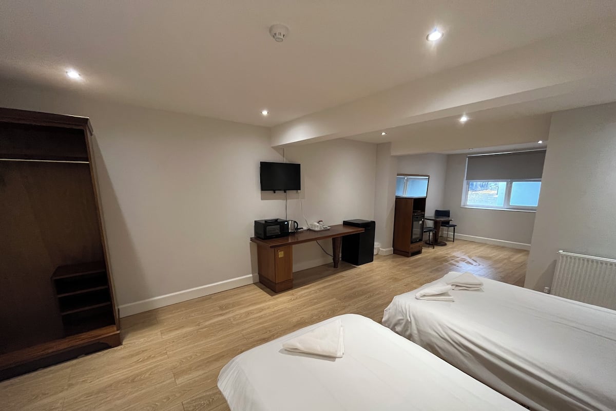 A hotel room with two beds, a desk with a computer, a TV, and a wardrobe.