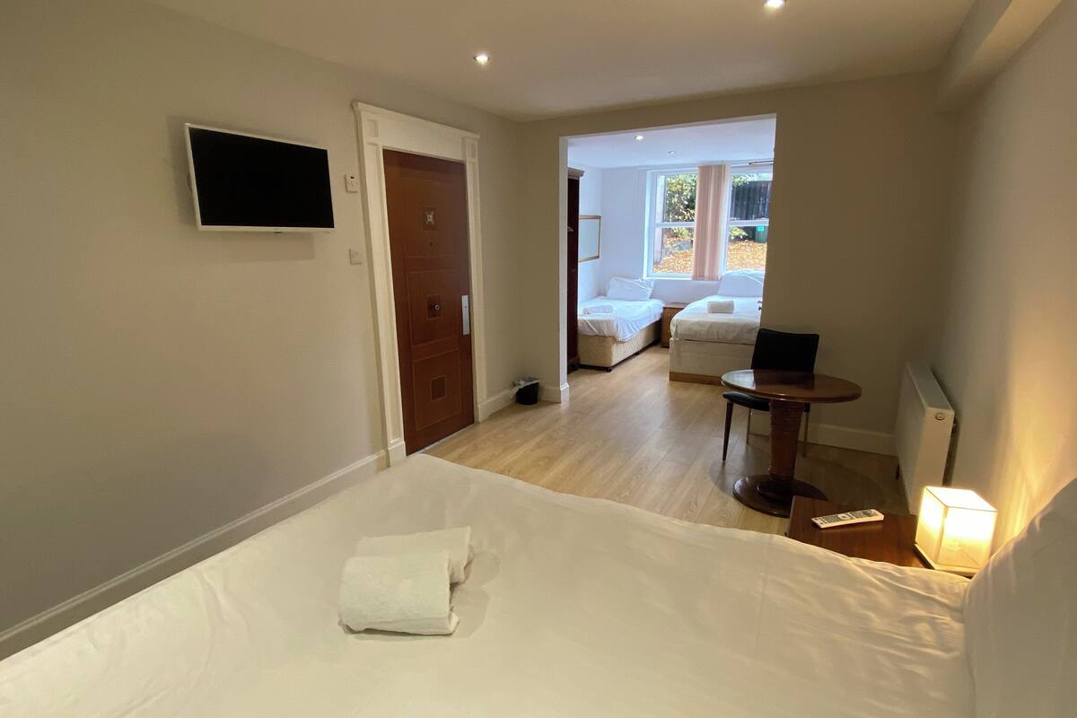 A hotel room with a bed, a desk, a chair, a TV, and a window with a view of the outside.