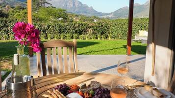 A table set for a meal with a view of mountains and a vineyard.