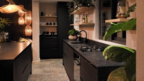 A modern kitchen with dark cabinetry, a central island, and built-in shelves. - Private Villa with pool in Cape Town (Cape Town)