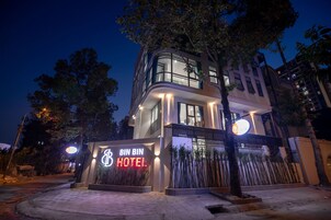 Un hotel moderno con una entrada destacada, amplias ventanas y una fachada bien iluminada.