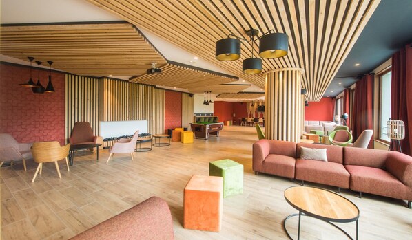 A spacious lobby with a modern design, featuring a mix of seating areas, a reception desk, and a visible staircase leading to upper floors. - Serene Apartment in Villarembert (Villarembert)