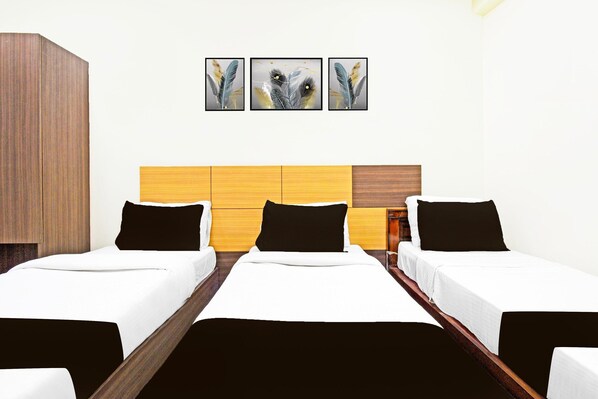 Habitación de hotel con dos camas individuales, cabecero de madera y tres cuadros enmarcados en la pared.
