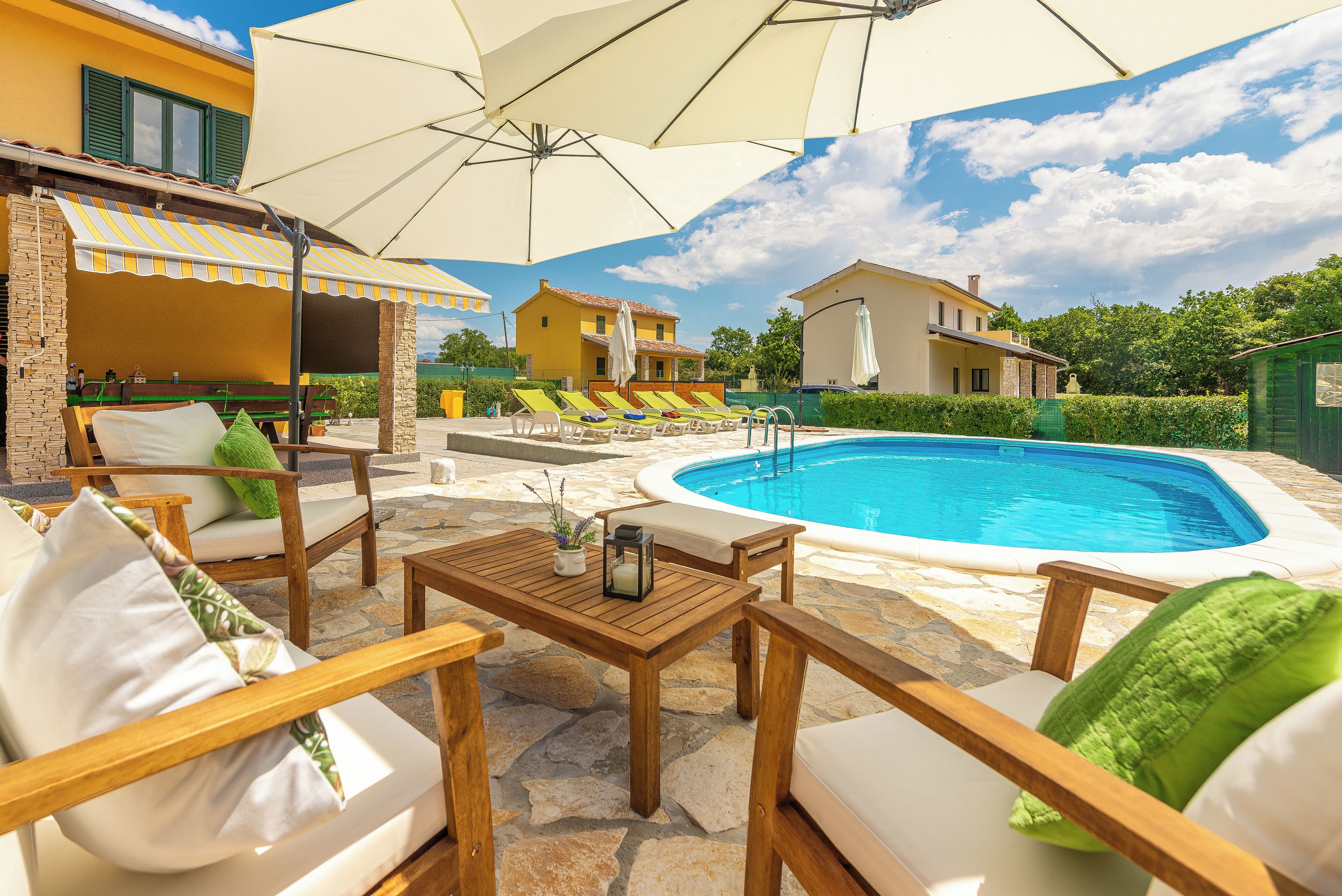 A poolside area with lounge chairs, a wooden table, and umbrellas.